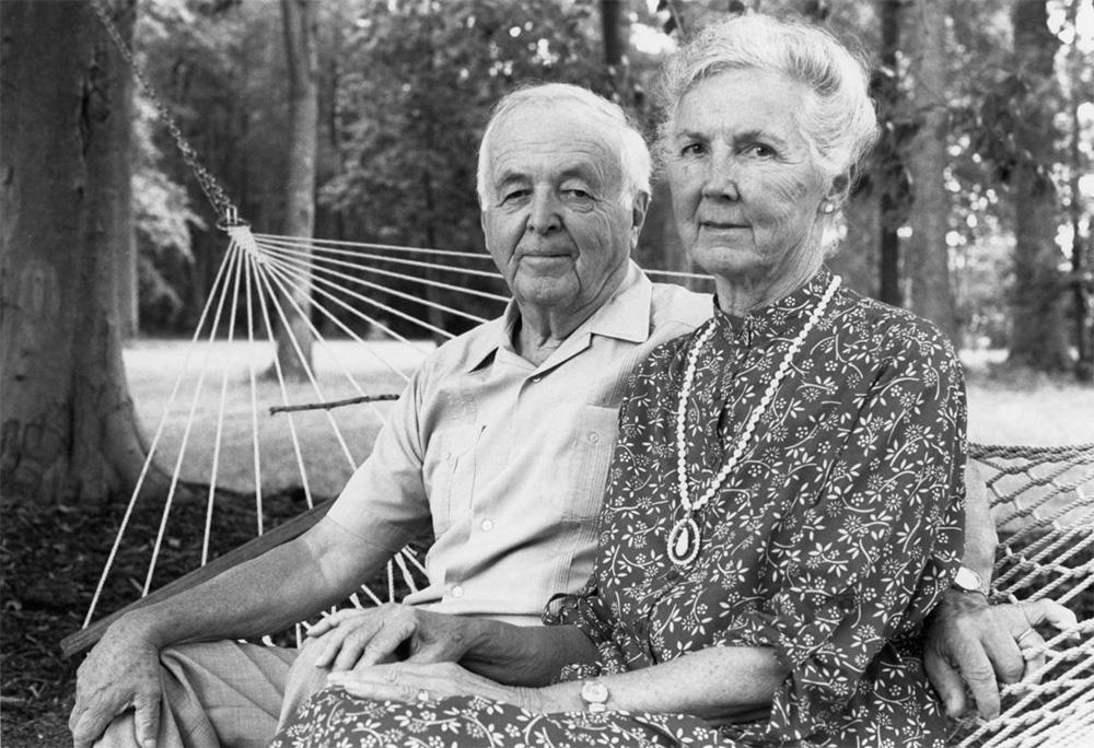 Black and white photo of Helen and Edwin Lynch sitting outside in a hammock among trees.